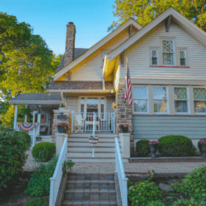 Vinyl Clapboard Siding in Cream with Stone Accents and Light Blue Shake Siding on Lower Half, featuring White Trim and Decorative Window Grilles