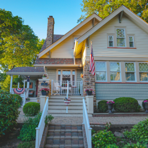 Vinyl Clapboard Siding in Cream with Stone Accents and Light Blue Shake Siding on Lower Half, featuring White Trim and Decorative Window Grilles