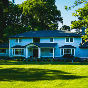 Light Blue Vinyl Shake Siding with Vertical Board and Batten in White Trim, featuring Black Metal Roof Accents and Symmetrical Bay Windows